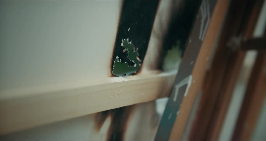 Smoke billows out from the charred holes in an art canvas on an easel
