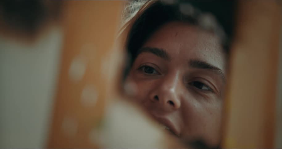 A woman is seen in a mirror talking and smiling