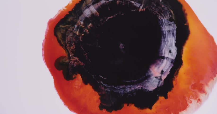 Black liquid spreads over the middle of the orange liquid