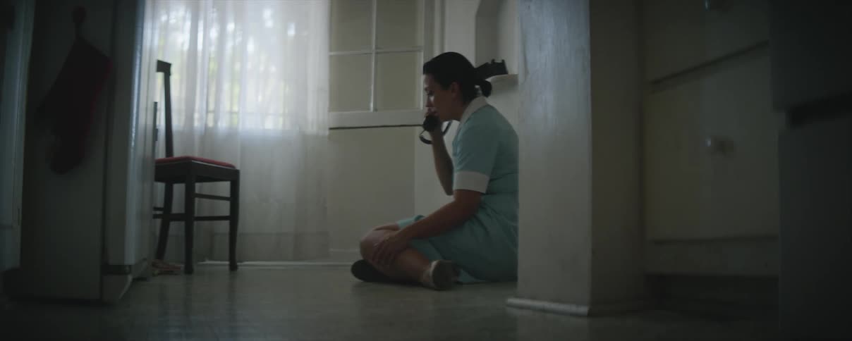 A woman wearing a maid uniform is talking on the phone when she suddenly collapses to the floor