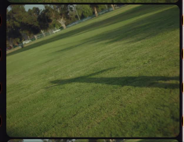 Female dancer with red hair blue top and sports pants dances on the lawn in public park