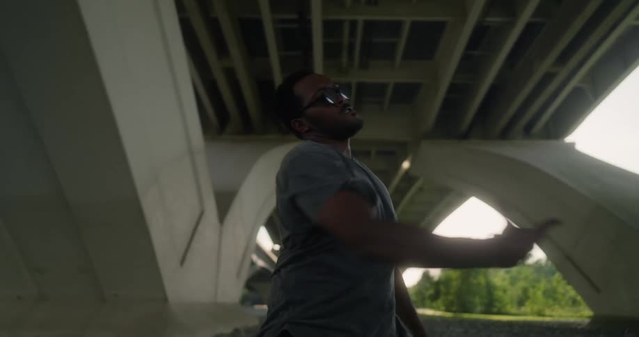 A man dances around under a bridge