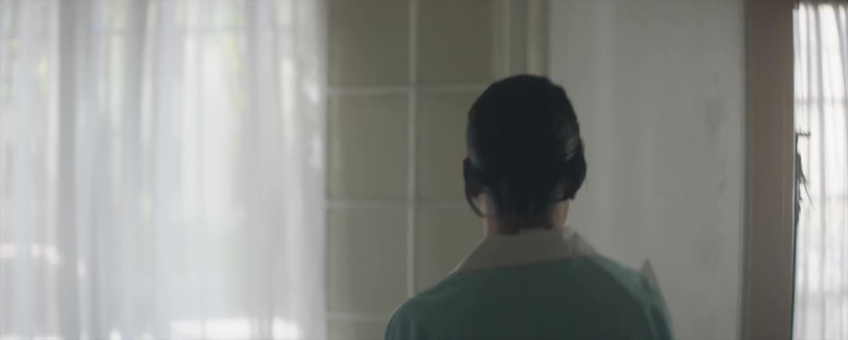 A woman wearing a maid uniform walks down the hall into the kitchen and answers the phone