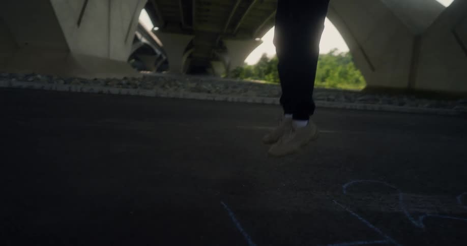 Man jumps up and down in place while exercising under a bridge