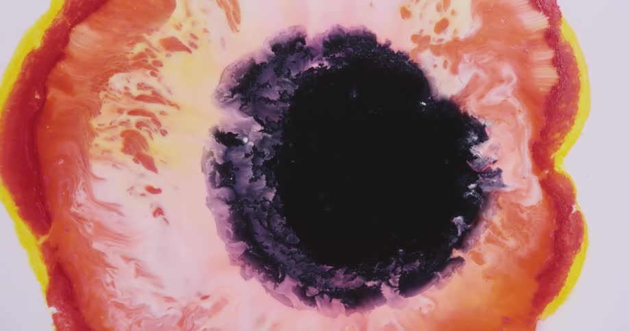 Dark liquid ink blooms mixing with surrounding red and yellow ink