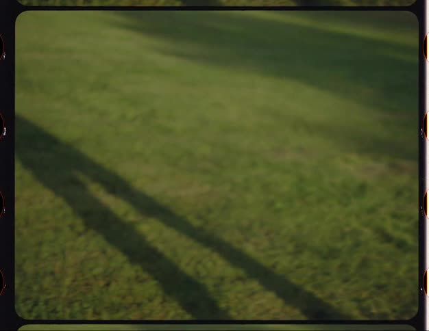 As female dances in the park her shadow stretches across the grass