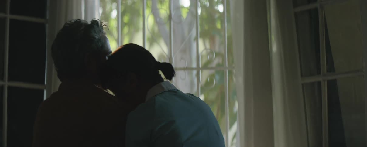 Man and woman look lovingly at each other and kiss as the sunlight streams through the window