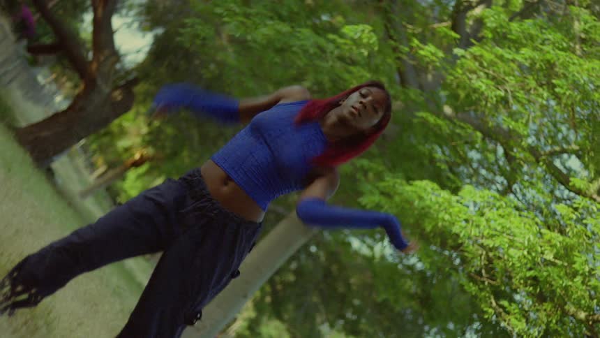 A young woman looks into the camera while dancing in a woodland