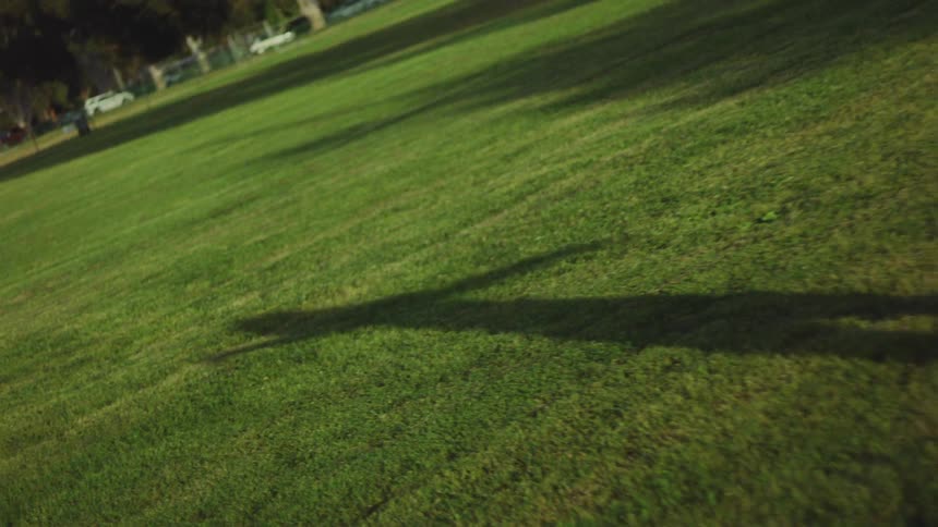 Long shadows trail as the sun is going down in a park where a woman dances