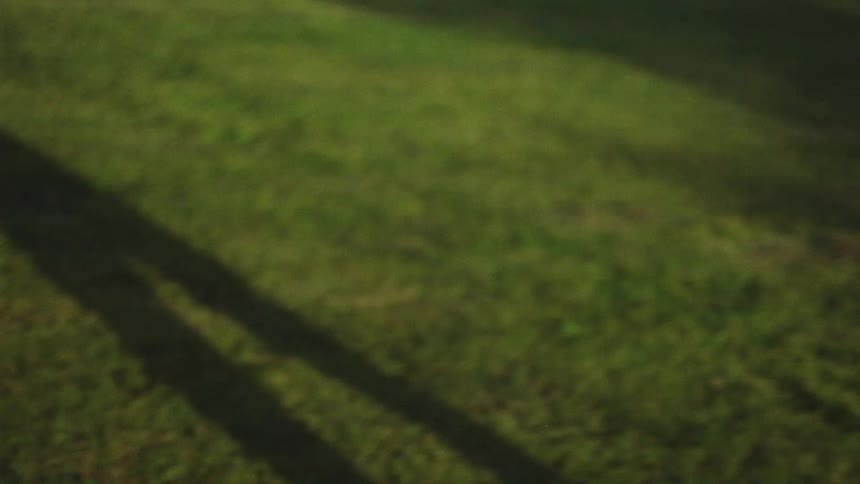 Female dancer with red hair blue top and sports pants dances on lawn in public park