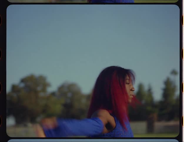 Woman with red hair and blue top dances to music in public park