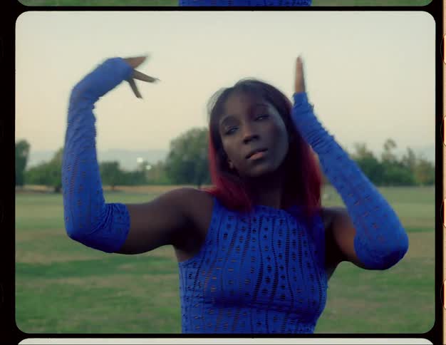 Young woman with red hair dances on a park at morning caught on vintage film
