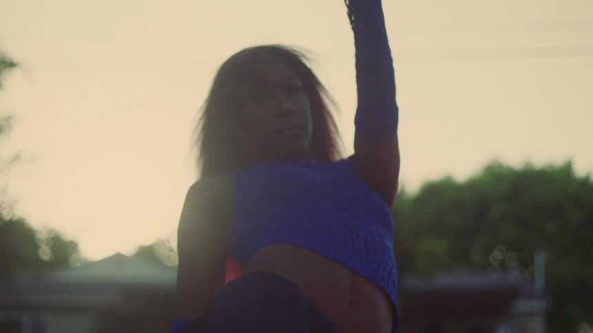 Woman with red hair blue top and sports pants dances on lawn in public park