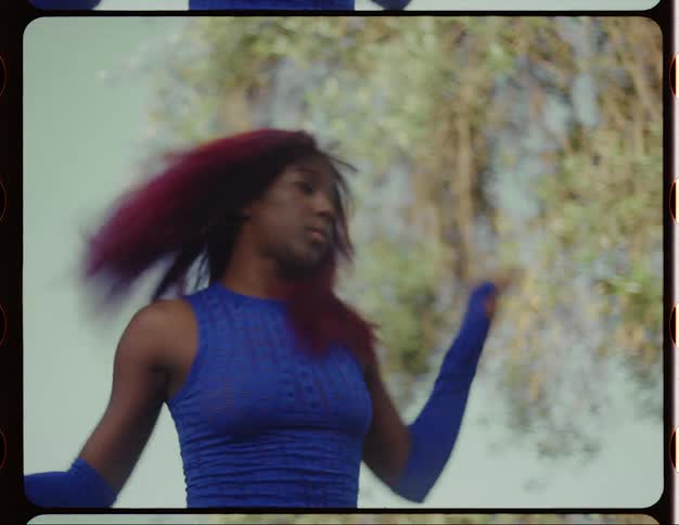 Young woman with red hair dances on a park at morning caught on vintage film