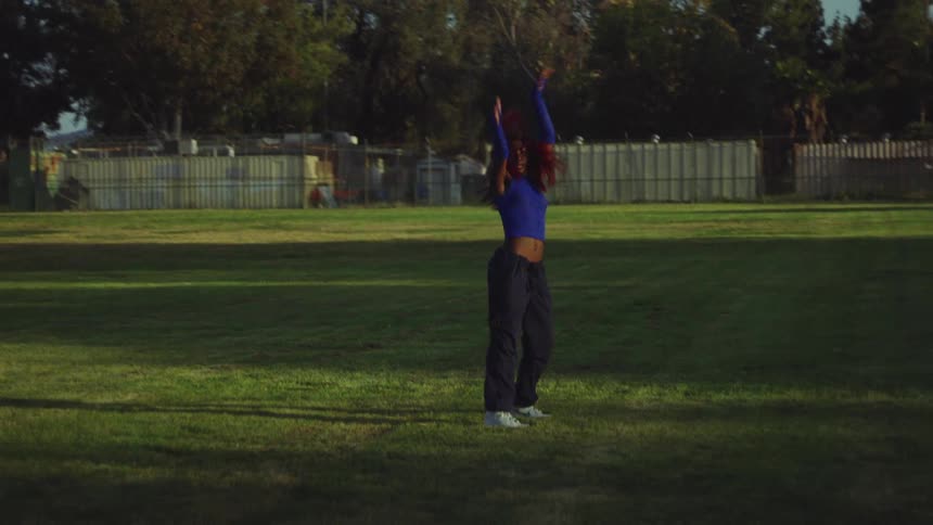 A woman dances outdoors in a field during the day