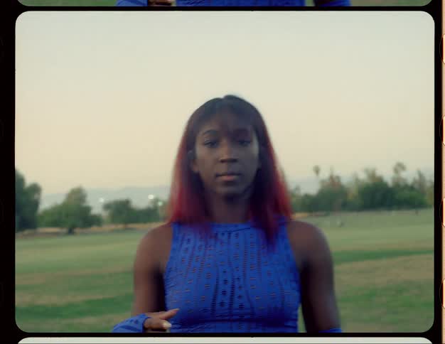 Young woman with red hair standing on a park at morning caught on vintage film