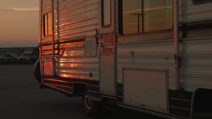 A recreational vehicle is parked in a lot at sunset