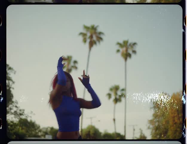 A teenage girl wearing a blue outfit is outside dancing on a neighborhood street