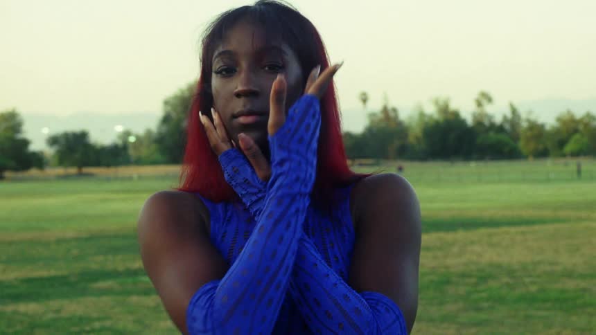 Female wearing blue moves through several poses while standing on lawn