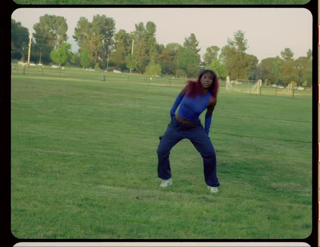 Woman wearing blue gloves dancing outdoors at a park