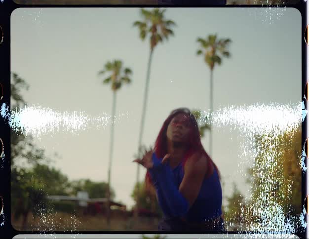A woman in a sparkly blue costume dances in a park