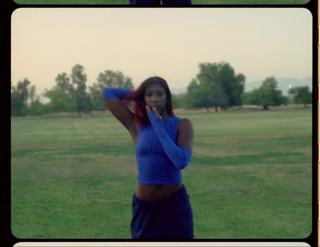 Young woman with red hair dances on a park at morning caught on vintage film