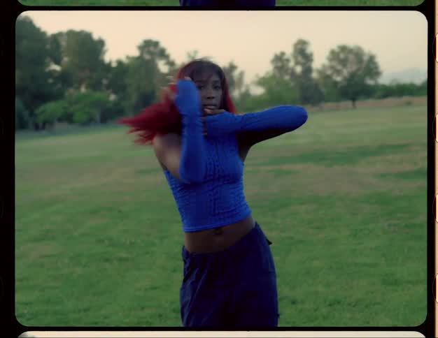 Female dancer dances in field under red tinted sky with mountains on the horizon