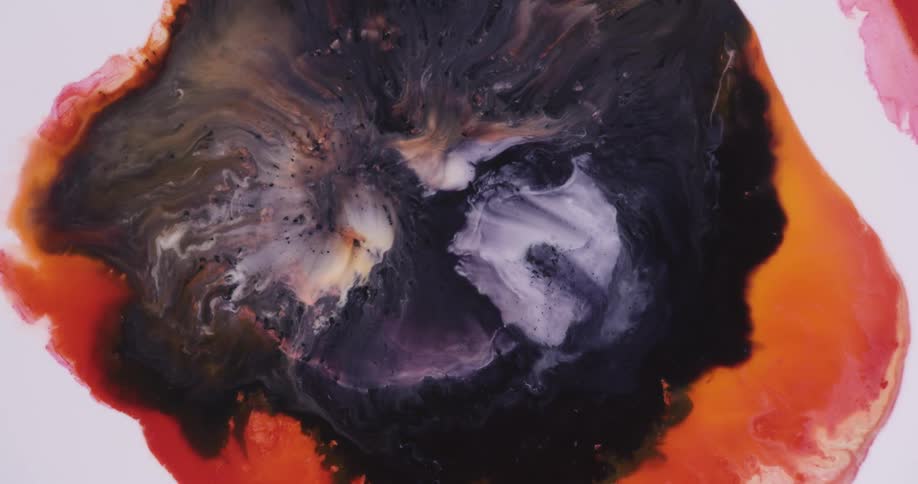 A liquid black center mixes and blends with light colors inside an orange ring as it grows across the white background