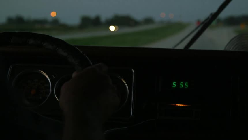 A car is traveling down a road at sunset