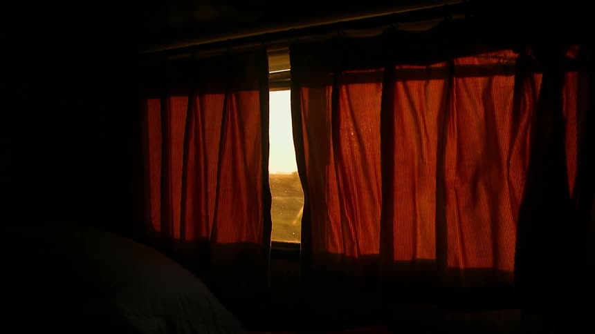 Passing scenery is seen through a part in curtains in an rv