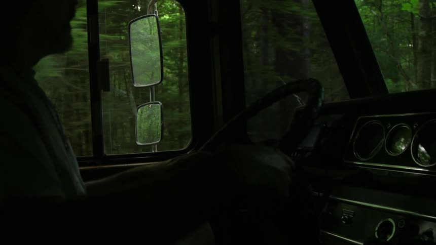 A man drives down a wooded road