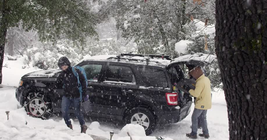 People are getting out of and unpacking a truck in the snow