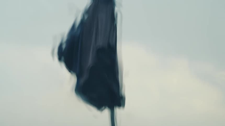 An umbrella blows in the wind as rain beats down on the window