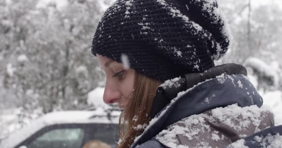 Smiling woman  standing in the snow with a man next to a car