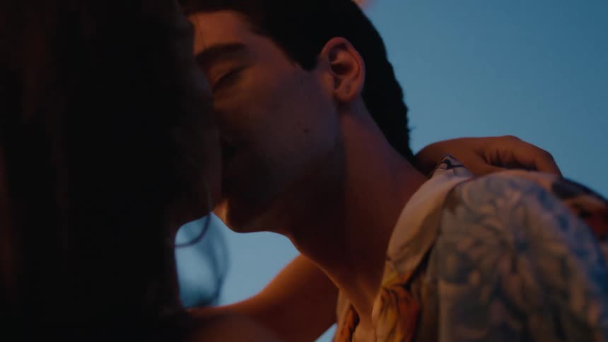 A man and a woman are standing outside near a building kissing and making out