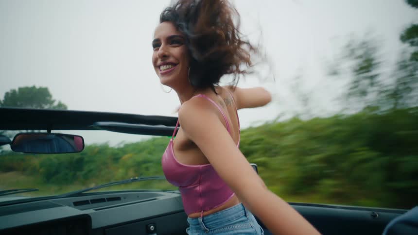 A woman dances and stands in the moving vehicle