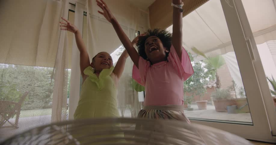 Two girls pretend to be blown back by air from house fan