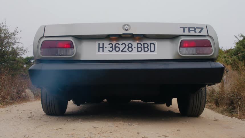 Gray sports car starts and drives off on dirt road