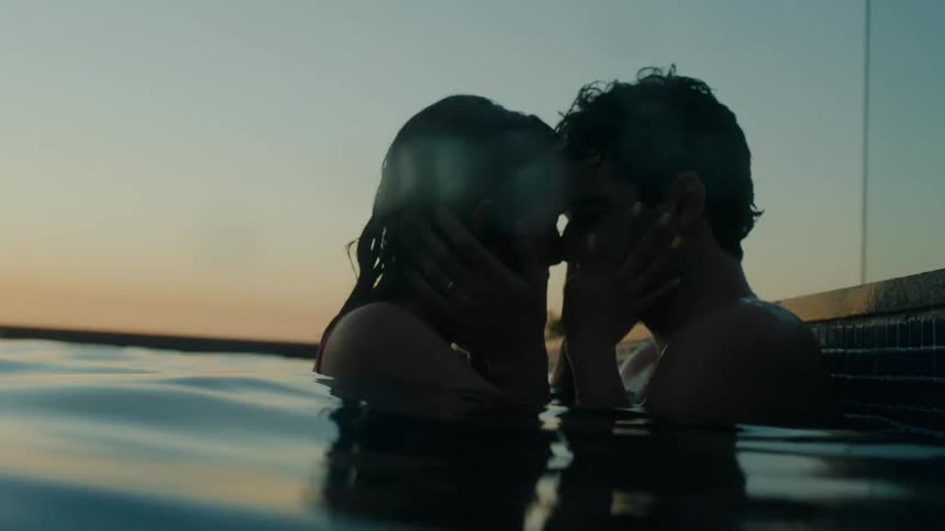 Man and woman make out in the swimming pool at dusk