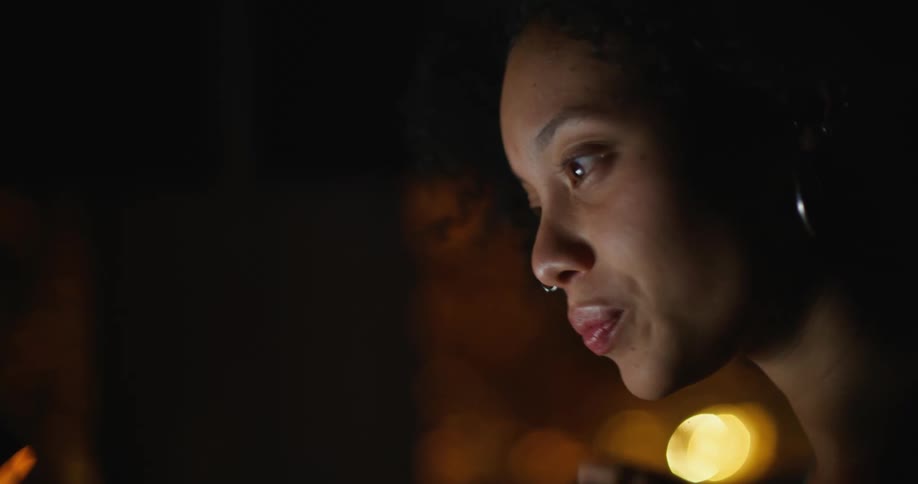 Light from screen brightens face of woman watching in dark room