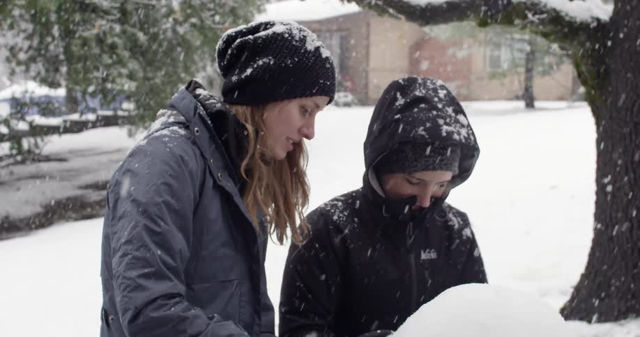 A woman and child build a snowman