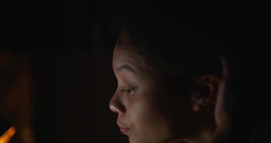 Tired woman sits at desk working on laptop at night