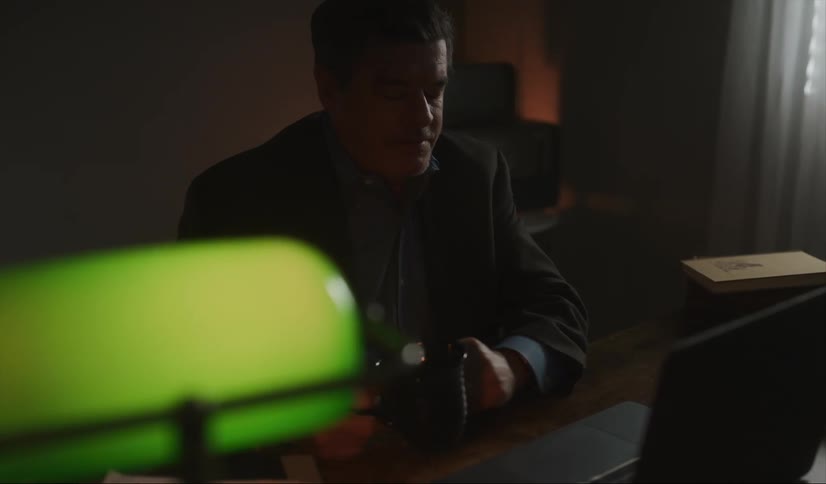 Man with black blazer jacket drinks from black cup making video call on laptop in room