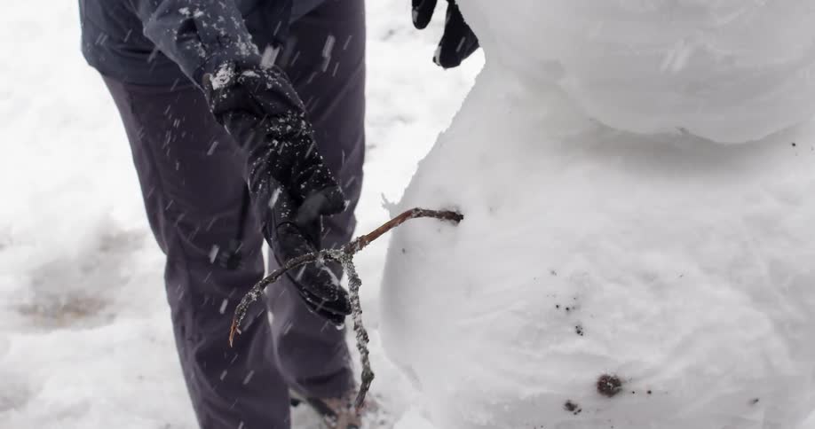 A man puts a stick into a snowman