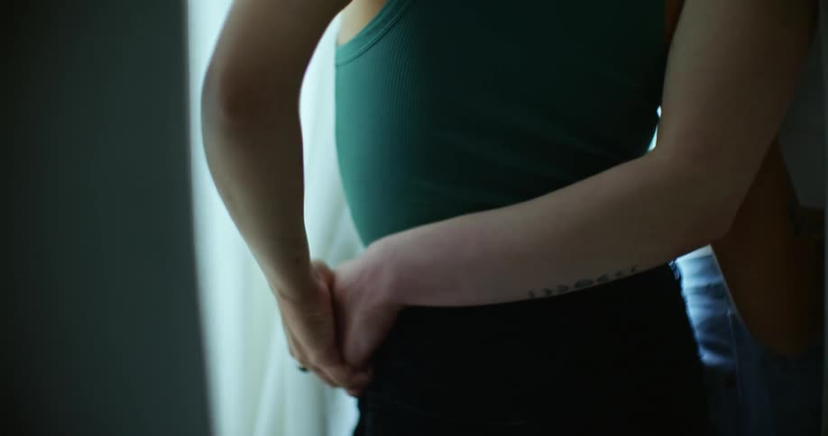 Two woman with their arms around each other standing at a window looking out