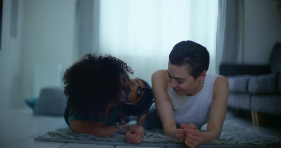 A couple laugh while lying on the floor with their dog