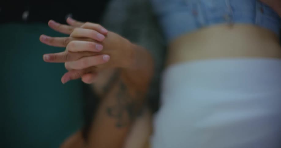 Two people recline together holding hands