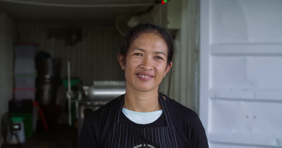 A restaurant chef smiles while standing in front of a storage room