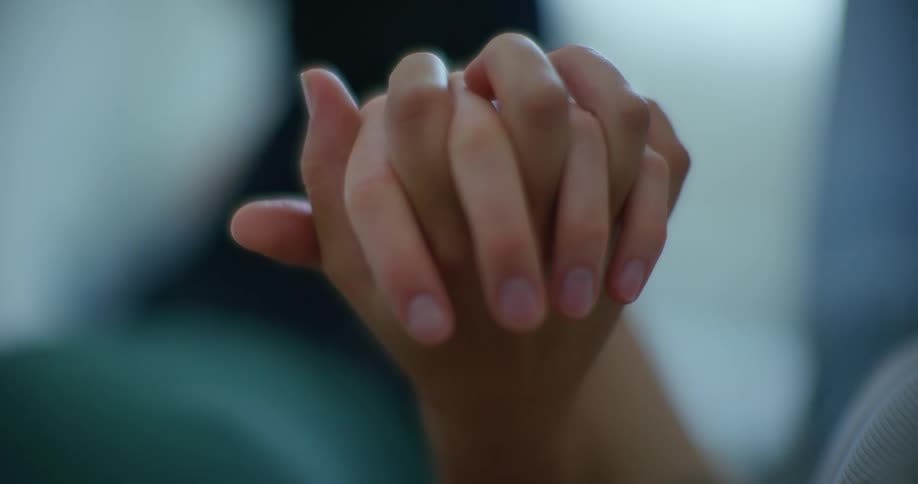 Close up of two people recline together holding hands