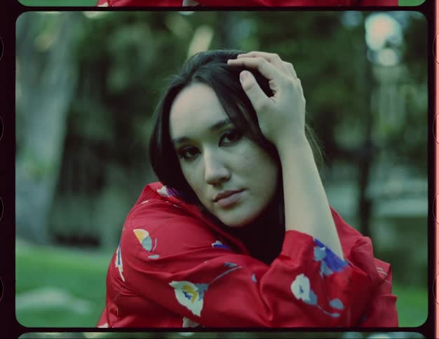 A woman is sitting in a park surrounded by trees